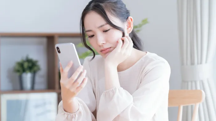 スマホを見ながら悩む女性